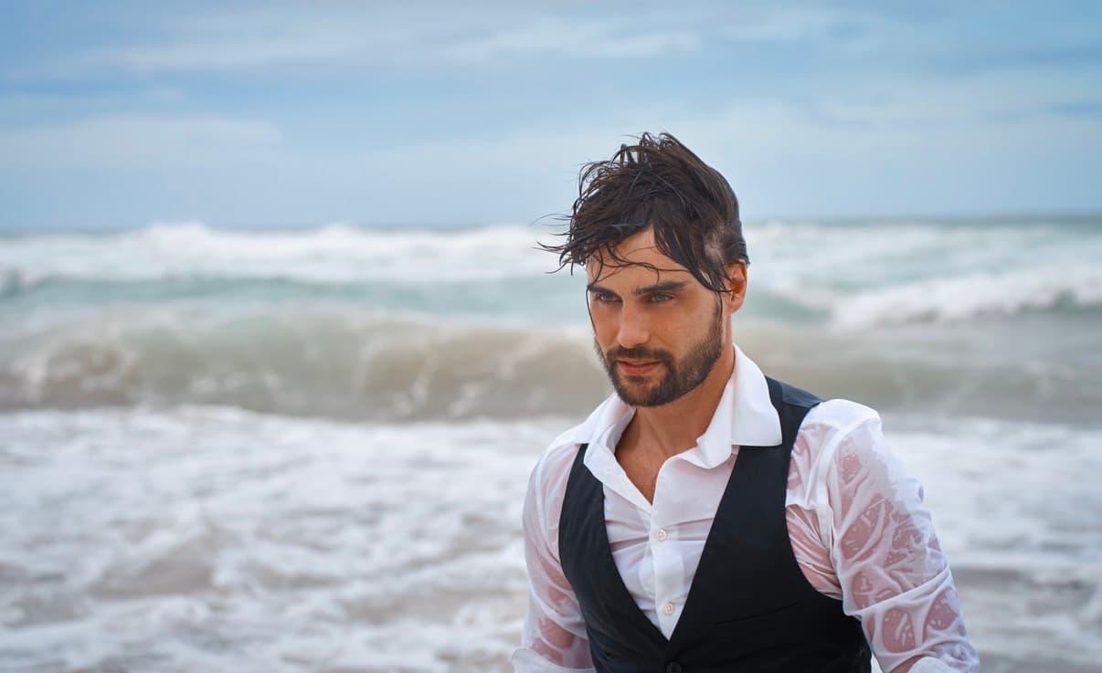 Stephen Manas standing in ocean waves during the 2323 Miami visual sequence with Kseniya Wagner